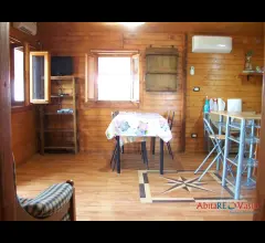 Chalet in legno, arredato, con giardino circostante.